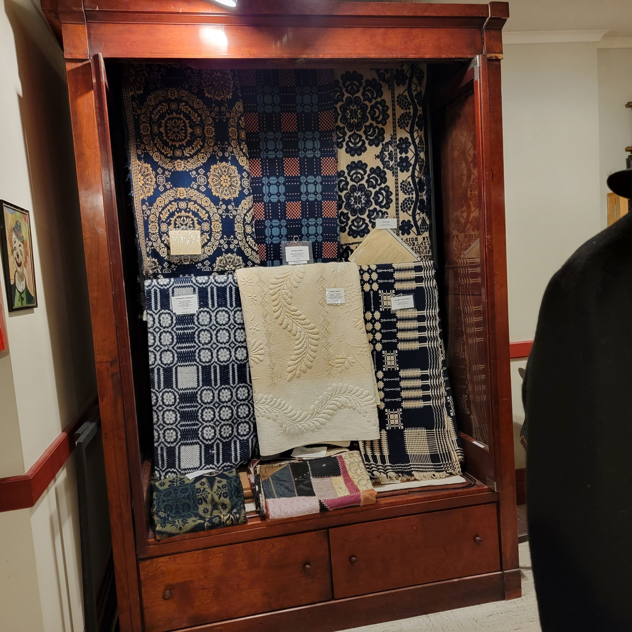 Cabinet of woven jacquard coverlets and quilts