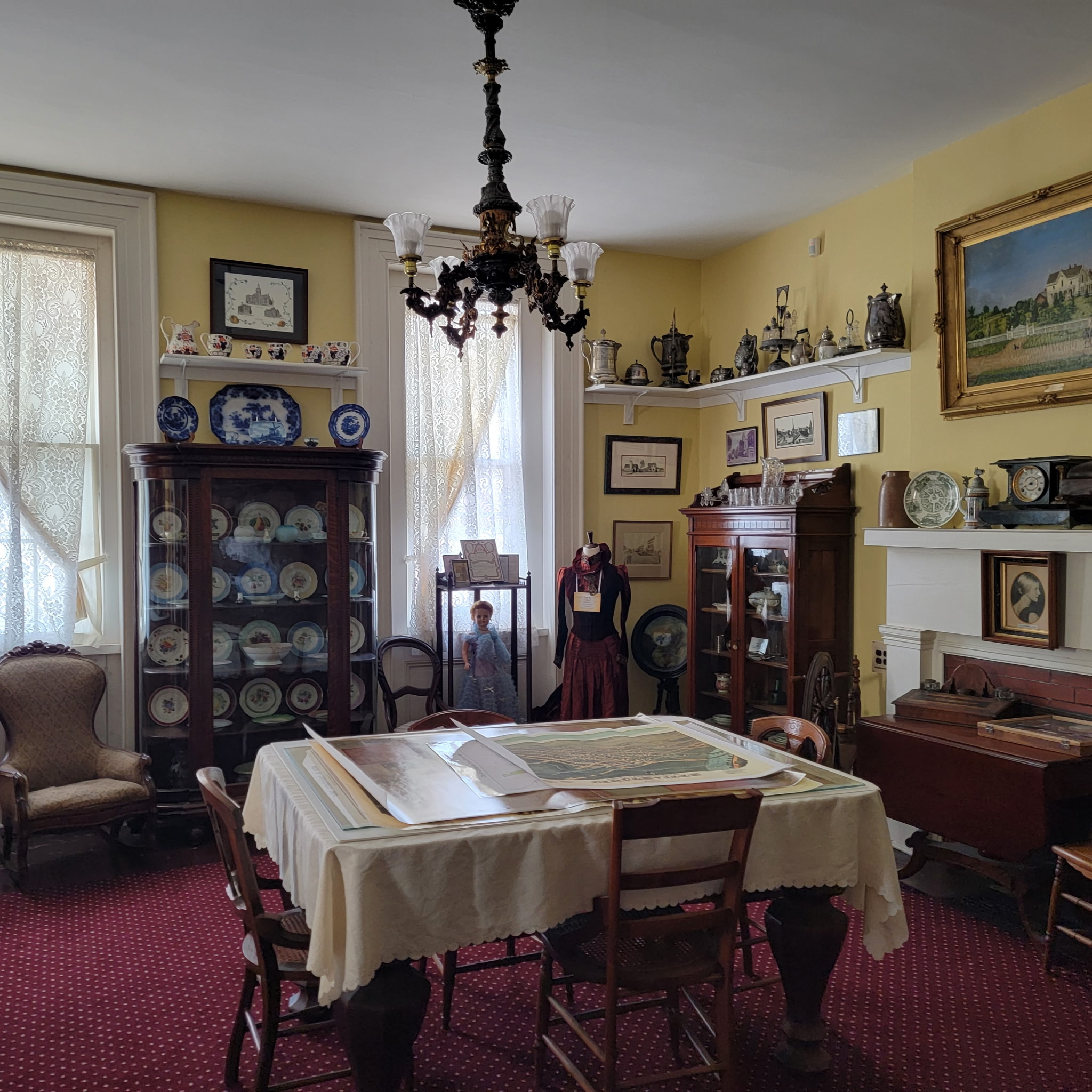 Yellow dining room with china cabinets, chandelier and map table