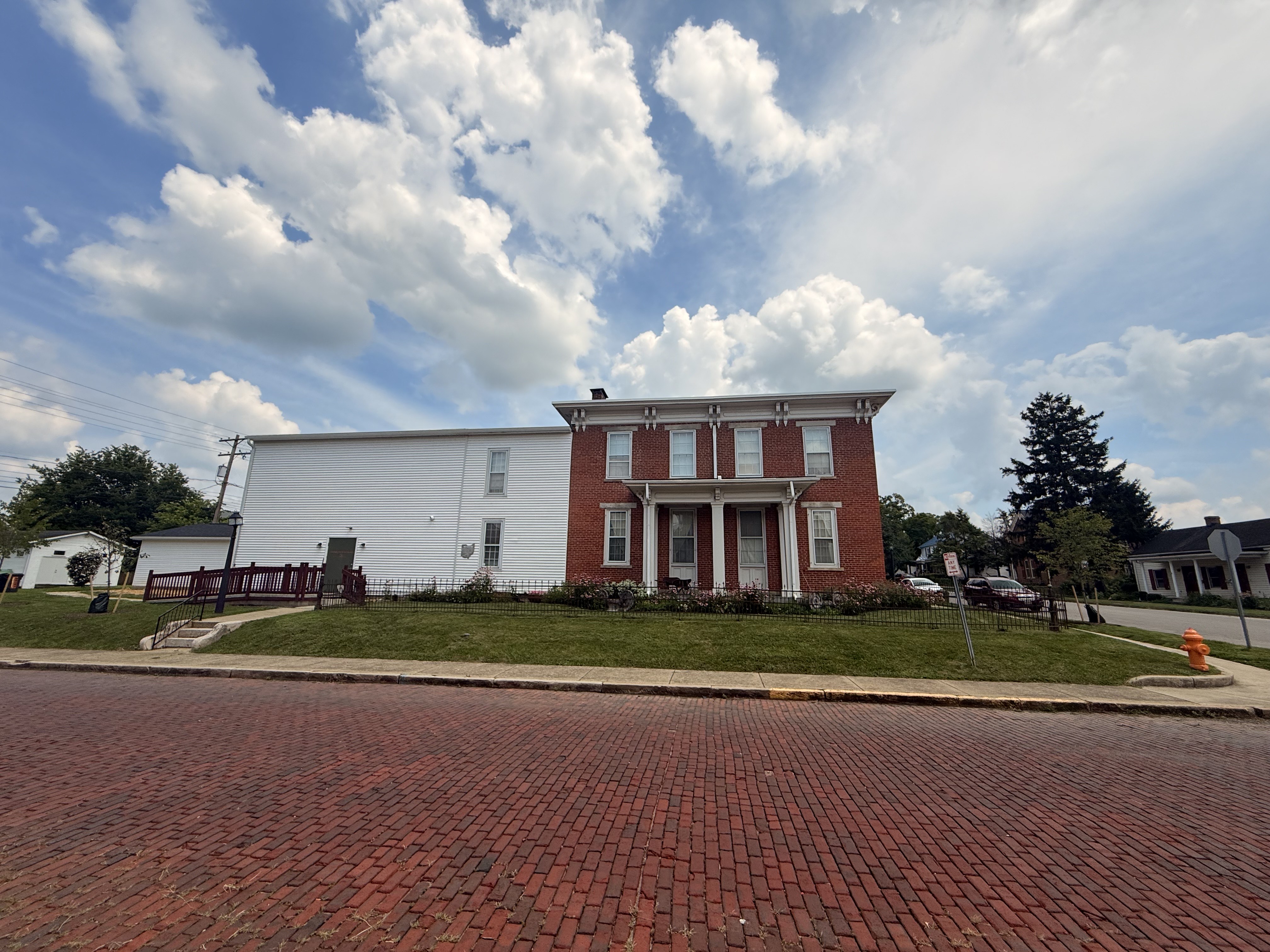 The museum seen across the brick street, brick house with frame addition
