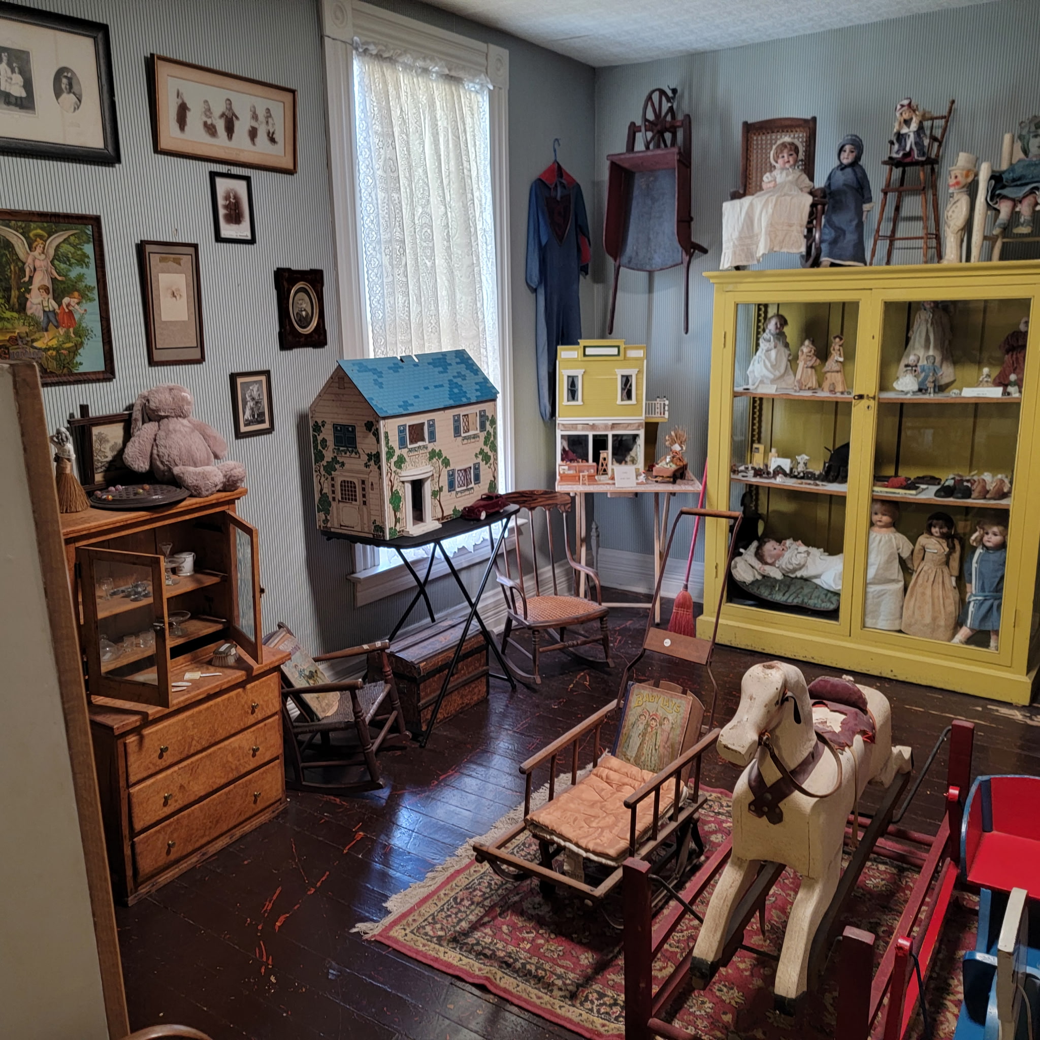 Toy room with dollhouses, a rocking horse and cases of antique dolls
