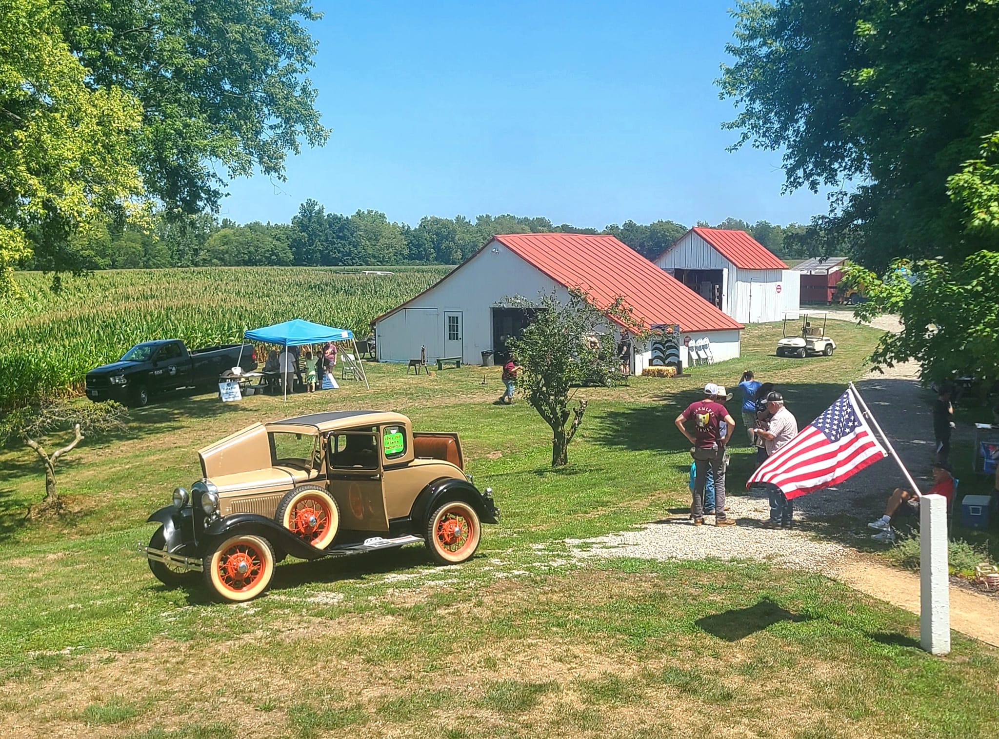 Visitors, a Model A car and display barns at the Down on the Farm event